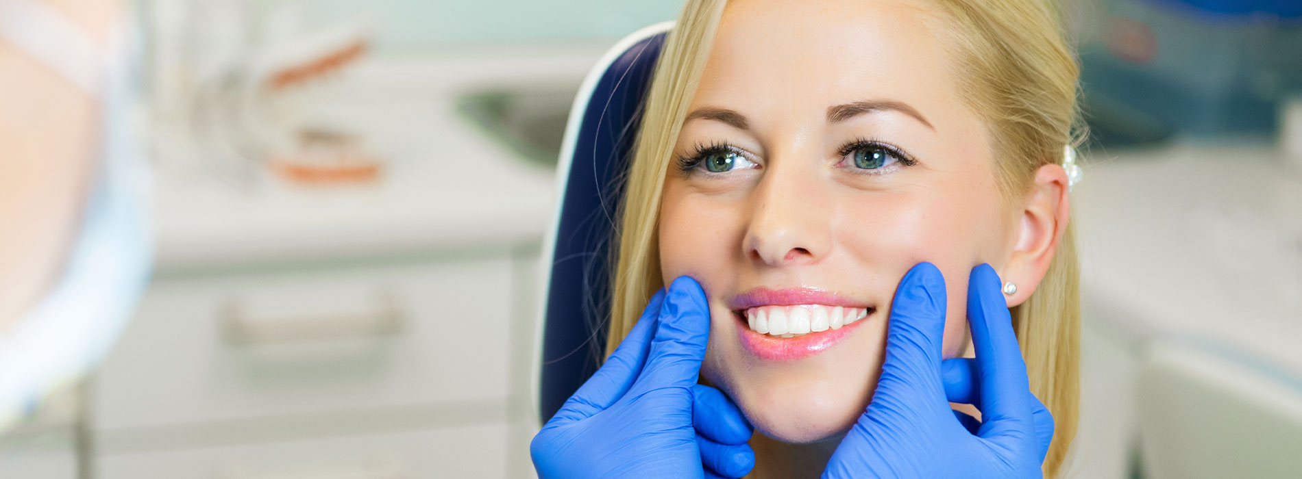 A woman undergoing dental care with a dentist s hand holding her chin.
