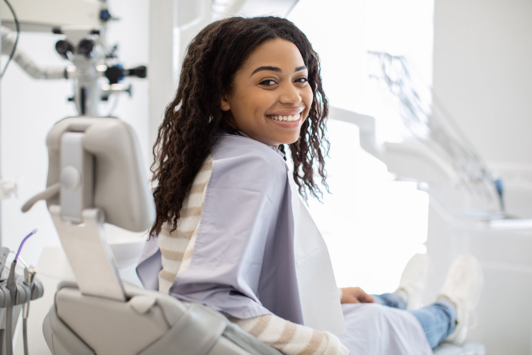 A smiling woman sitting in a dental chair.