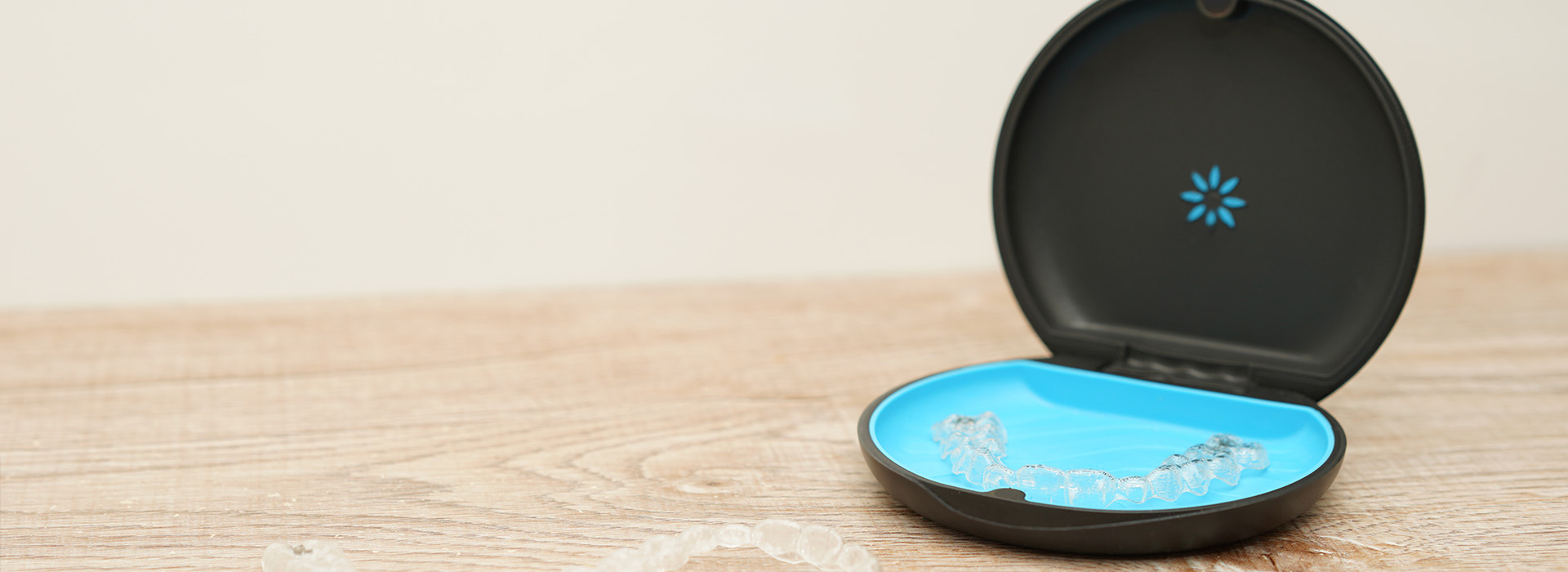 The image shows a small, blue object with a circular design placed on top of another round item, both set against a blurred background.