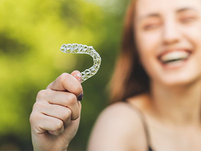 The image shows a smiling person holding up a toothbrush with a bristle-like design.
