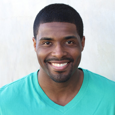 An elderly couple poses for a photo with smiles on their faces, embracing each other against a scenic backdrop.