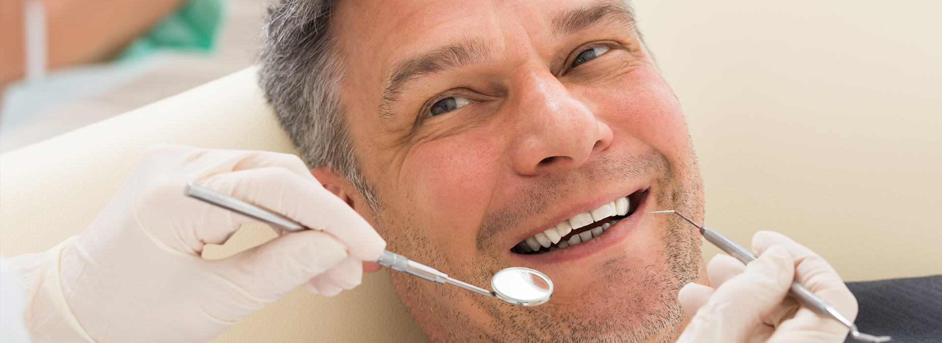 A man receiving dental care with a smile on his face, surrounded by dental tools and equipment.