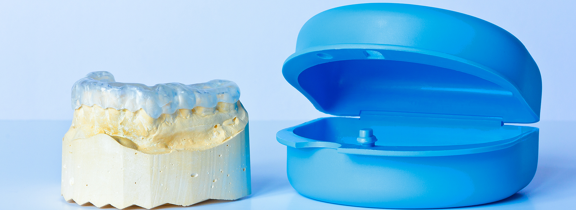 The image shows a blue dental implant on the left and a yellow-brown dental crown on the right, both against a white background.