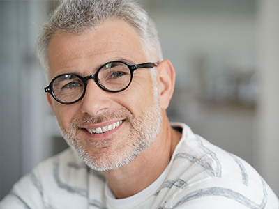The image features a man with glasses smiling at the camera, taken from two different angles   one showing him from the front, and another from the side.