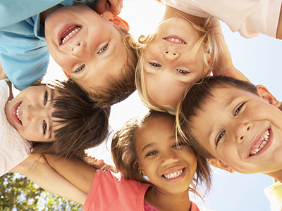 The image shows a group of children with diverse expressions, posing together for a photo with their arms around each other.