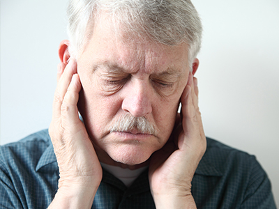The image shows a man with his hand on his face, looking distressed or in pain.